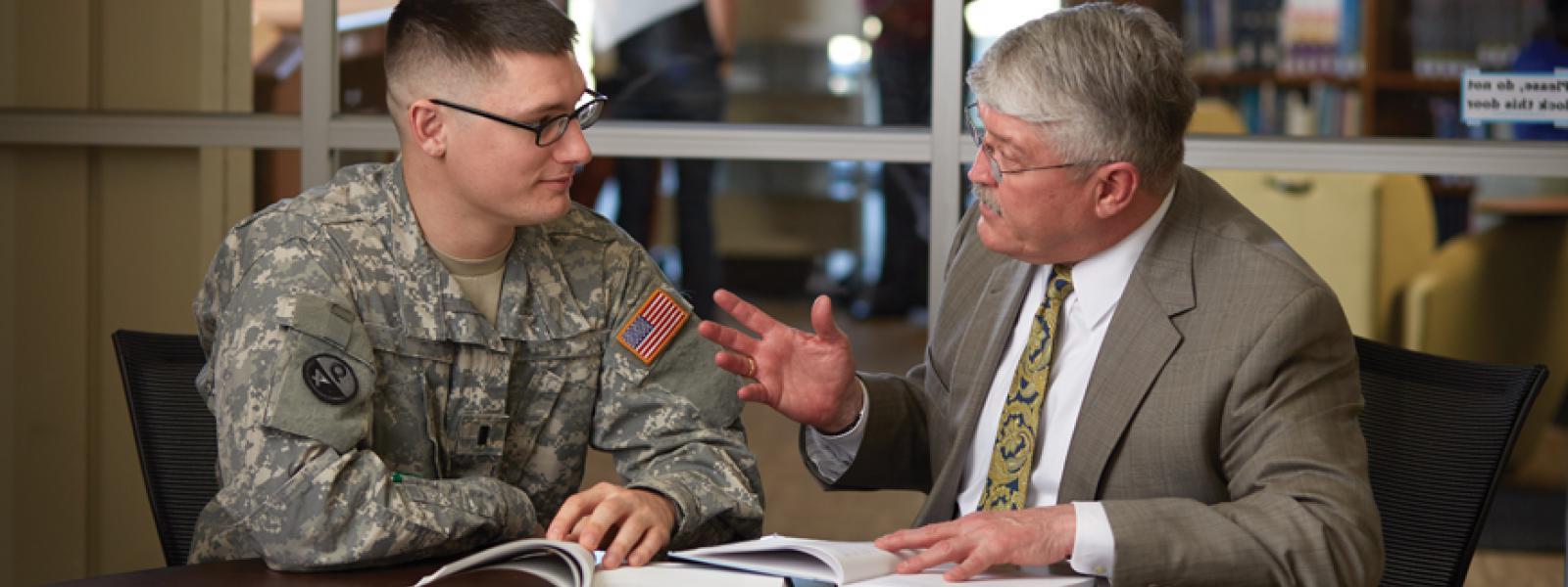 A seminary professor speaking with a military chaplaincy student in an office environment.